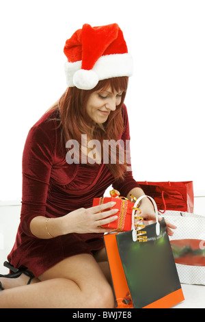 Das Mädchen in eine Weihnachts-Mütze sitzt unter Pakete mit Einkäufen Stockfoto