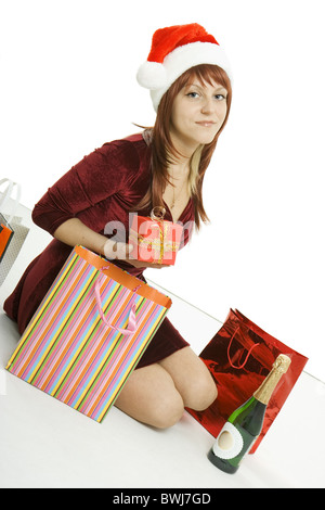 Das Mädchen in eine Weihnachts-Mütze sitzt unter Pakete mit Einkäufen Stockfoto