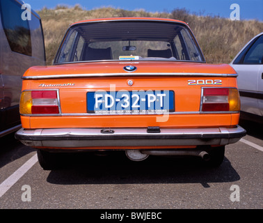 Rückseite einer orange Vintage BMW automatische 2002 auf einem Parkplatz in der Nähe der Dünen von Scheveningen, den Haag, NL Stockfoto