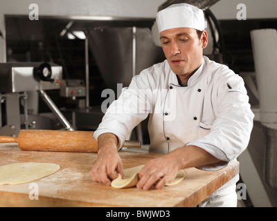 Baker ausrollen Teig in einer Bäckerei Stockfoto