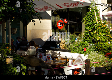 Gäste unter Sonnenschirmen im Café im freien Bürgersteig Patio in Leipzig Altstadt Stockfoto