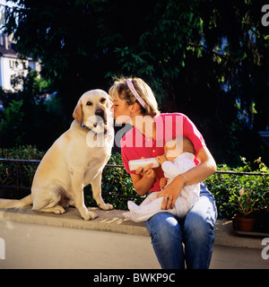 HERR JUNGE MUTTER MIT DER FLASCHE FÜTTERN IHR BABY UND LABRADOR GOLDEN RETRIEVER HUND Stockfoto