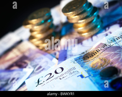 Britische Pfund-Münzen gestapelt im Hintergrund auf einem Bett aus zwanzig Pfund-Noten Stockfoto