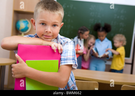 Bild von smart Schuljunge Blick in die Kamera Lächeln auf Hintergrund von Klassenkameraden Stockfoto