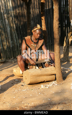 Zulu Mann arbeitet Holz, Shakaland Zulu-Dorf, Nkwalini Tal, Kwazulu Natal, Südafrika. Stockfoto