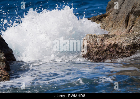 Splash. Eine Welle schwappt, da es einen schmalen Spalt zwischen zwei Felsen auf einer karibischen Insel trifft Stockfoto