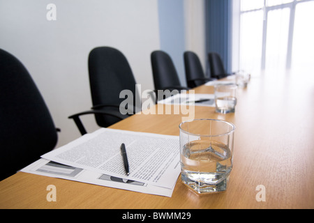 Bild von Glas Wasser am Arbeitsplatz mit Papier, Stift und Sessel in der Nähe von Stockfoto