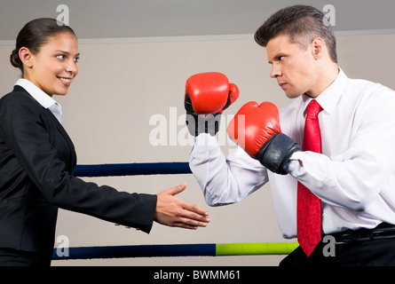 Porträt von aggressiven Geschäftsmann in Boxhandschuhe kämpfen mit positiven Weibchen mit ihren Arm gestreckt für handshake Stockfoto