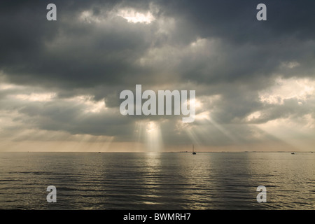 Sonnenstrahlen piercing die Wolken und mit Silber reflektieren Licht auf dem Meer in einem kalten Tag im November Stockfoto