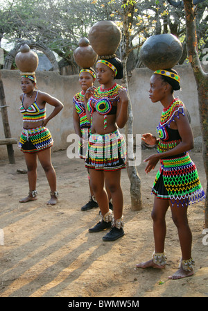 Zulu Mädchen tragen Perlen Tracht und Durchführung Töpfen auf ihre Köpfe, Shakaland Zulu-Dorf, Kwazulu Natal, Afrika Stockfoto