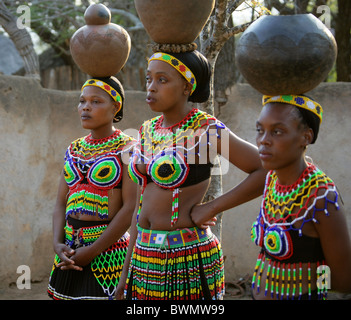 Zulu Mädchen tragen Perlen Tracht und Durchführung Töpfen auf ihre Köpfe, Shakaland Zulu-Dorf, Kwazulu Natal, Afrika Stockfoto