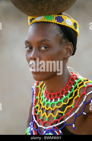 Zulu Mädchen tragen Perlen Tracht und Durchführung Töpfen auf ihre Köpfe, Shakaland Zulu-Dorf, Kwazulu Natal, Afrika Stockfoto