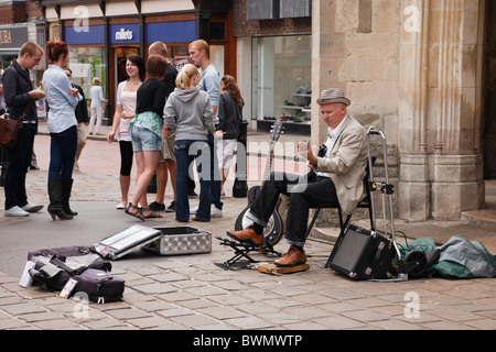 Straßenbuscher, der Gitarre spielt, um Geld von Old Market Cross im Stadtzentrum von Chichester, West Sussex, England, Großbritannien zu sammeln Stockfoto