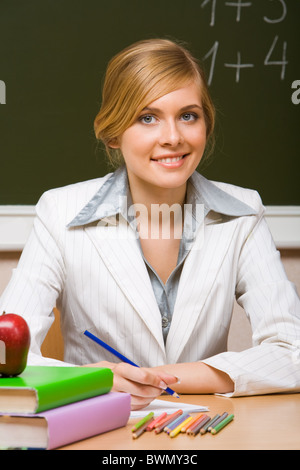 Porträt des jungen Lehrers Copybook Bücher in der Nähe von mit Blick in die Kamera Lächeln nachschauen Stockfoto