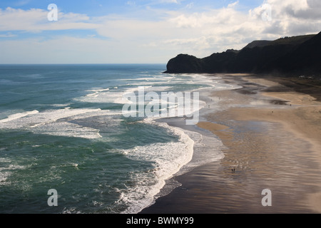 Menschen zu Fuß am Strand mit Brandung Wellen Rollen, Piha, Neuseeland Stockfoto