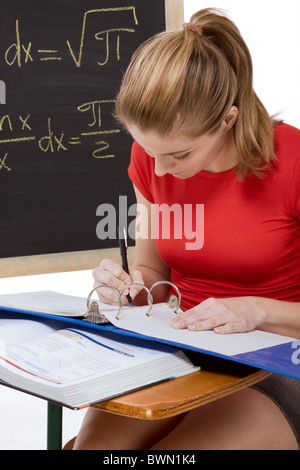 High School oder College Studentin sitzen am Schreibtisch im Math-Klasse. Tafel mit fortgeschrittenen mathematischen Formeln Stockfoto