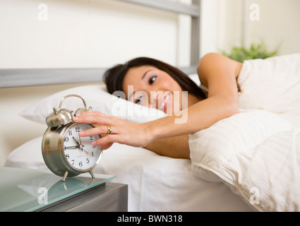 USA, Illinois, Metamora, junge Frau im Bett Wecker ausschalten Stockfoto