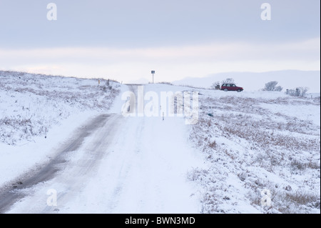 Eine schneebedeckte Straße an den Rändern der Ilkley Moor. Stockfoto