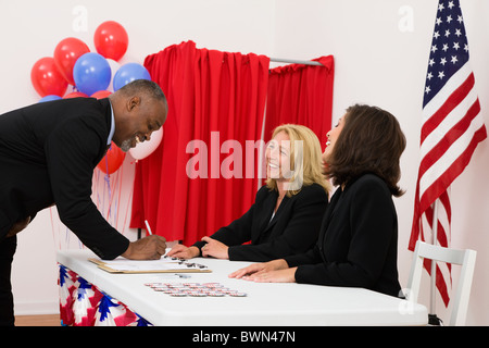 USA, Illinois, Metamora, Menschen bei Umfragen legen Tabelle, US-Flagge, Luftballons und Wahlkabine im Hintergrund Stockfoto