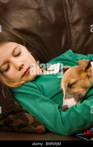 kleines Mädchen schläft mit ihrem neuen Welpen Stockfoto