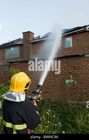 Feuerwehrmann mit Schlauch Aufsprühen von Wasser auf Feuer Feuerwehr & Service GB Stockfoto