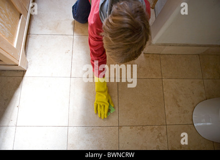 Kind Badezimmerboden mit Handschuh und Schwamm reinigen Stockfoto