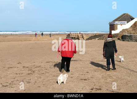 zwei Frauen gehen Hunde am Strand von Perranporth in Cornwall, Großbritannien Stockfoto