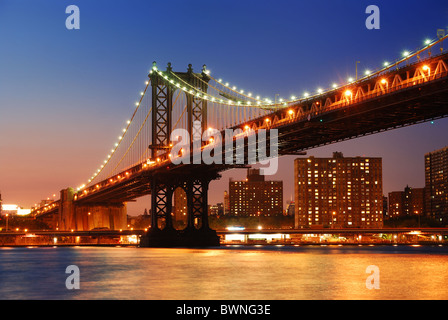 New York City Manhattan Bridge über den Hudson River mit Skyline nach Sonnenuntergang Nachtansicht mit Lichtern beleuchtet aus Brooklyn angesehen. Stockfoto