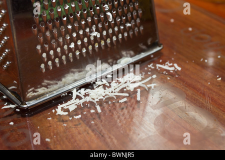 Splitter aus geriebenem Parmesan neben getragen Käsereibe. Stockfoto