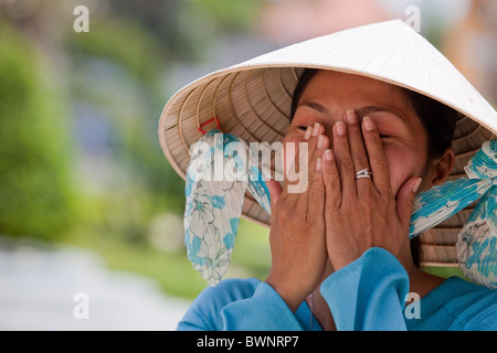 Vietnamesin, trägt einen traditionellen konischen Hut, Lauging und bedeckte ihr Gesicht. Stockfoto