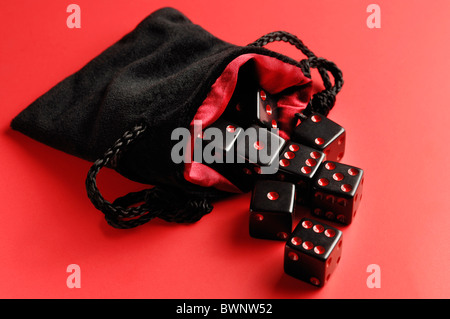 Set of black dice in a pouch isolated on red background Stockfoto