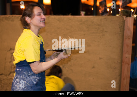 Paris, Frankreich, Messe, Salon Batir Ecologique, Green Building Products, Frau arbeitet manuell, Strohwand mit Schlamm bedecken, energieeffizientes Zuhause Stockfoto