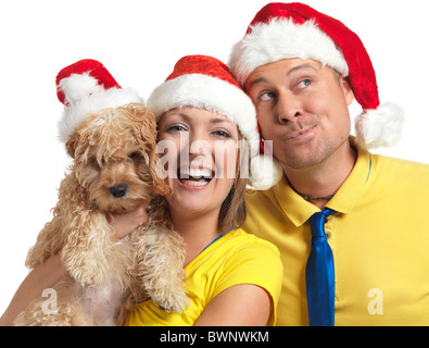 Führerschein erhältlich unter MaximImages.com - Porträt eines glücklichen jungen Mannes und einer Frau mit einem Cockapoo-Hund in ihren Händen, der rote Weihnachtshüte trägt. Stockfoto