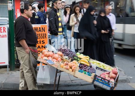 Türkei Istanbul Sultanahmet zwei Frauen das Tragen von Burka und Schleier vorbei an frischem Obst stall mit männlichen Verkäufer auf stark befahrenen Straße Stockfoto