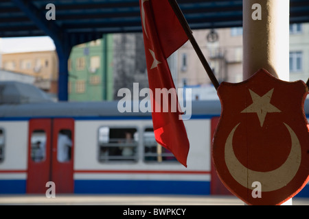 Türkei Istanbul Sultanahmet Sirkeci Gari Terminal Bahnhof, türkische Flagge und Wappen im Vordergrund mit dem Zug am Bahnsteig Stockfoto