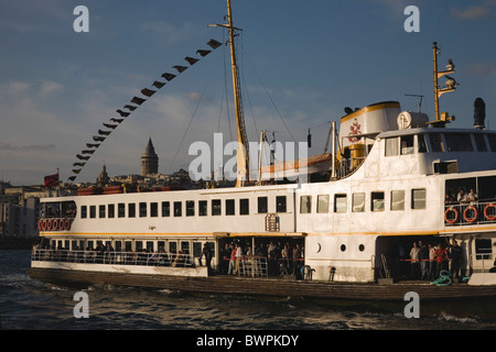 Türkei Istanbul Sultanahmet überfüllte Fähre unter türkischer Flagge auf den Bosporus mit Stadt und Galata-Turm in Beyoglu hinter. Stockfoto