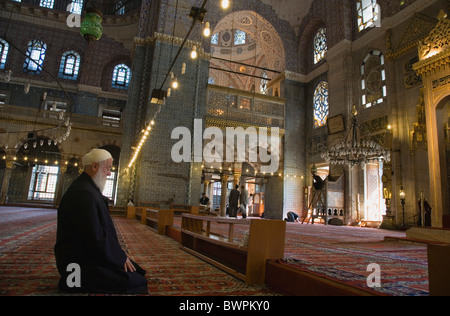 Türkei Istanbul Sultanahmet der neuen Moschee oder Yeni Camii gefliest und hoch dekorierten Innenraum mit älteren Mann, der betet Stockfoto