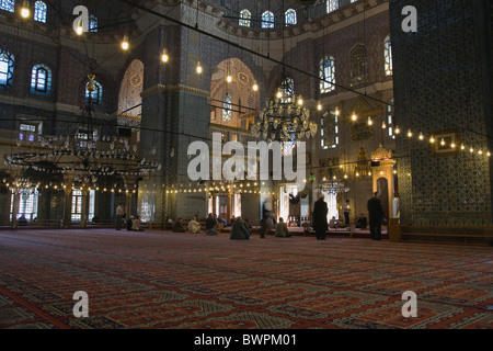 Türkei Istanbul Sultanahmet der neuen Moschee oder Yeni Camii gefliest und hoch dekorierten Innenraum mit Männer beim Gebet. Stockfoto