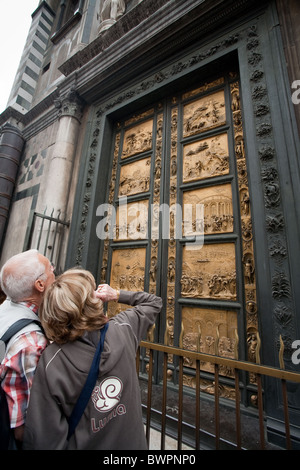 Reife Touristen bewundern die Bronzetüren von Lorenzo Ghilberti im Baptisterium Florenz. Touristen, die sich Kunst ansehen Stockfoto