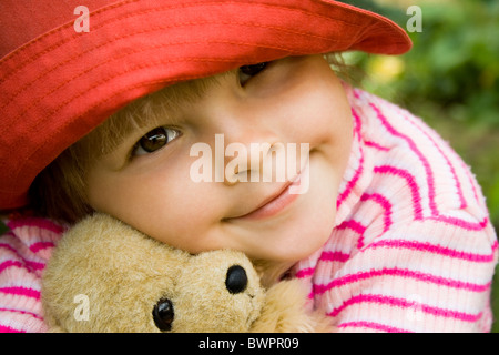 Leiter der girlie umarmt ihr Teddybär mit friedlichen Ausdruck Stockfoto