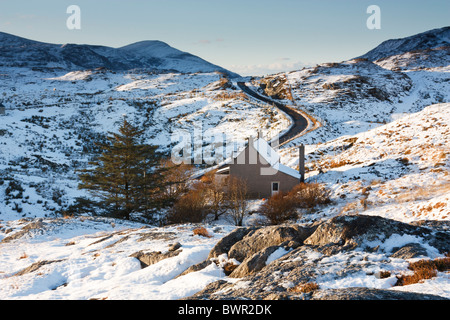 Einem einsamen Haus verträgt sich schlecht mit einer einspurigen Straße, die durch eine verschneite Tal schlängelt sich auf der Insel Harris, Schottland Stockfoto