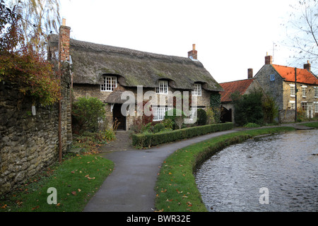 Reetdachhaus am Bach in Thornton-Le-Dale in North Yorkshire. Stockfoto