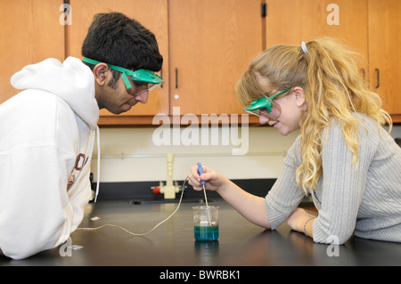 Studenten, die das Tragen von Schutzbrille dabei eine wissenschaftliches Experiment Messen der Temperatur einer chemischen Reaktion Stockfoto