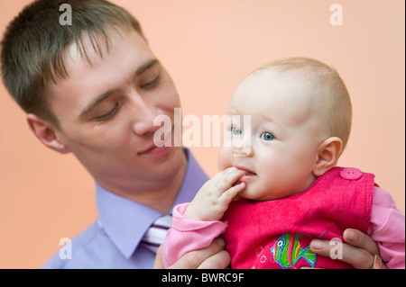 Europäische junger Mann schaut liebevoll seine kleine Tochter, die ihre Finger in den Mund nahm