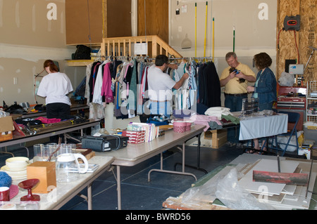 Ein Mann und eine Frau auf einem amerikanischen Garage Verkauf während der Eigenheimbesitzer mit einem Welpen spielen. Kansas, USA. Stockfoto