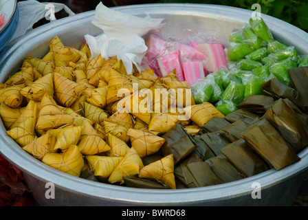 Bei einem traditionellen Markt in Ubud, Bali, ein Verkäufer zeigt, die einige balinesische Nachtisch ordentlich behandelt, eingehülltes Naturprodukte Stockfoto