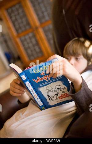 Acht Jahre altes Kind einen beliebten amerikanischen Roman, Diary of a Wimpy Kid lesen Stockfoto