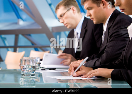 Reihe von ernsthaften Geschäftsleuten Notizen während der Konferenz Stockfoto