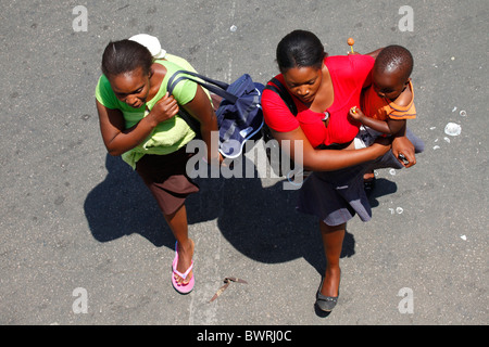 Zwei Frauen überqueren Sie eine Straße in Bulawayo, Simbabwe. Eine der Frauen trägt ein Kleinkind. Stockfoto