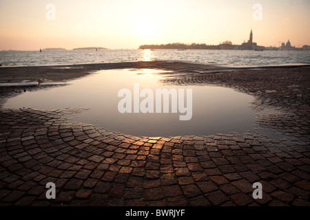 Eine Pfütze Überbleibsel von Überschwemmungen durch die Lagune bei Flut in das Abendrot in Venedig. Stockfoto